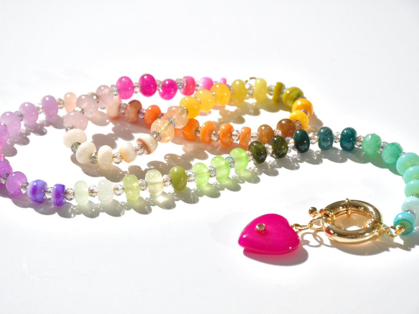 A rainbow multi-gemstone opal necklace that is hand-knotted Made from natural semi precious opal gemstones it features a hot pink heart pendant. It&#39;s feminine & girly w/ a hint of iridescence w/ the added glass shiny beads in between each gemstone.